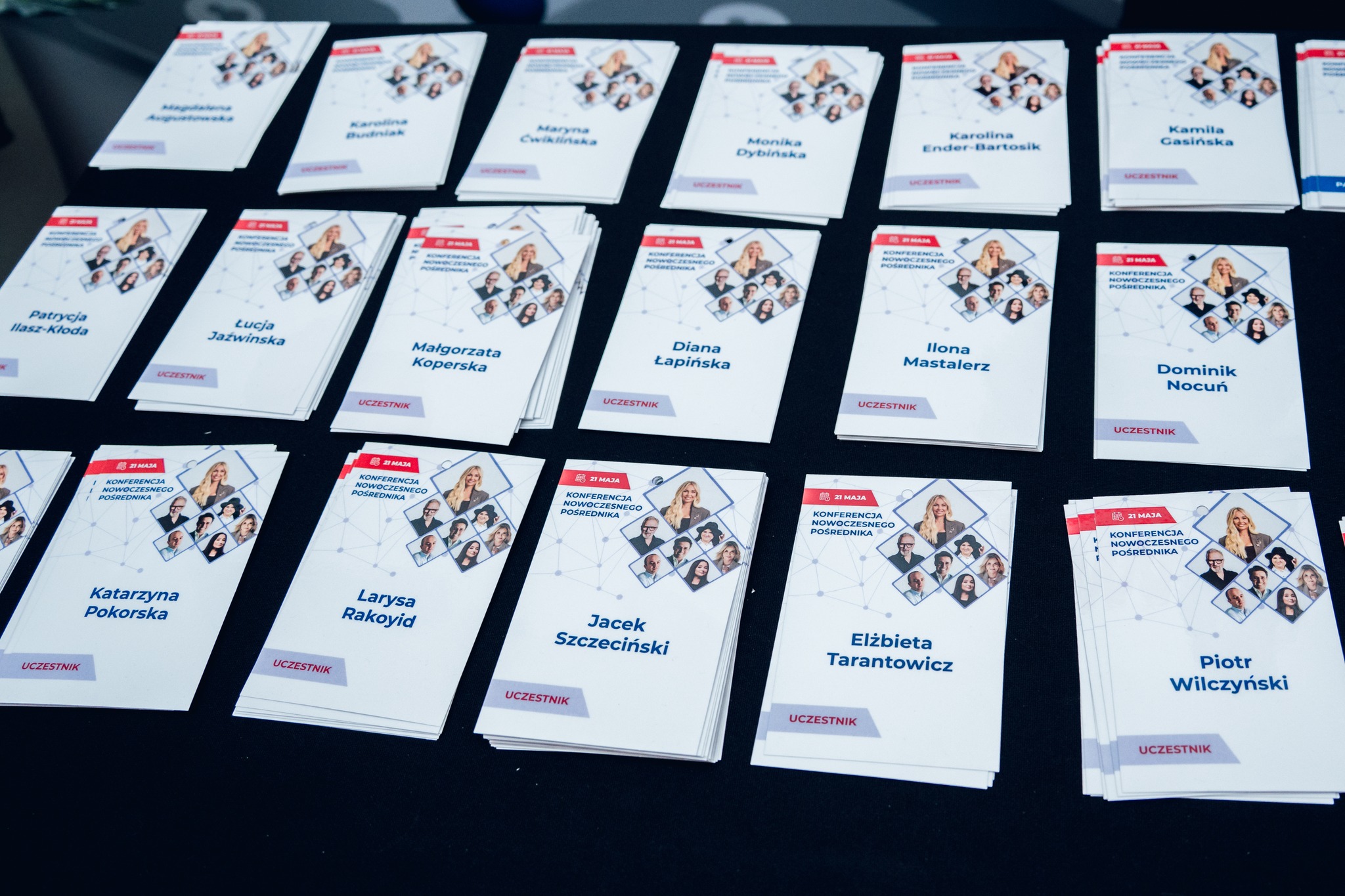 Close up of printed MLS conference name badges laid out in a grid, each with photo, name and colourful header design